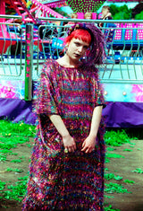 Model with red hair wearing the TINSEL Maxi Black and Multicoloured Shimmer kaftan Dress at the funfair