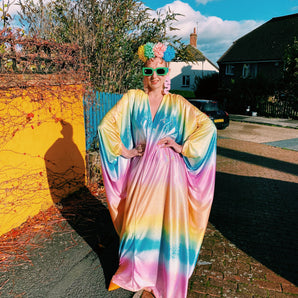 Model wearing a shimmering, liquid holographic maxi kaftan dress in pastel rainbow colors.