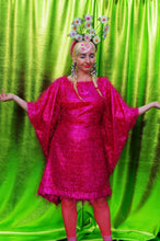 Load image into Gallery viewer, girl with blonde hair and plaits wears a pink shimmering tinsel mini dress with matching pink tights and heels against a metallic green backdrop
