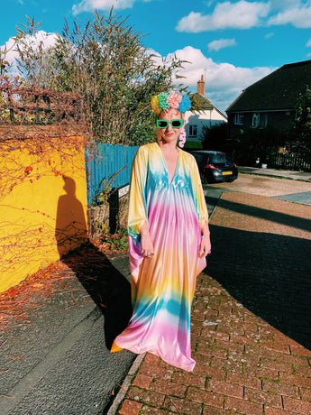 Model wearing a shimmering, liquid holographic maxi kaftan dress in pastel rainbow colors.