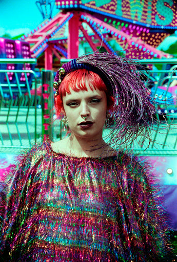 Close-up of the model wearing the TINSEL Maxi Black and Multicoloured Shimmer kaftan Dress at the funfair and matching headdress